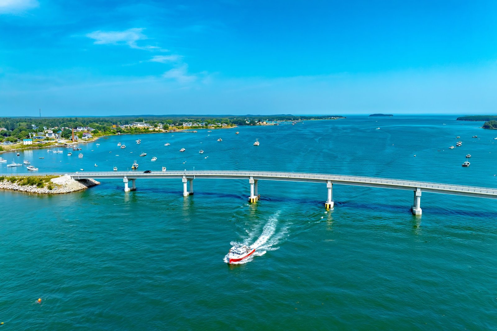 Sweeping panoramic view of bridge spanning turquoise bay with island community