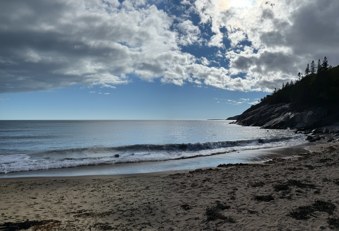 Cinematic panoramic view of Maine coastline with crashing waves, dramatic clouds, and silhouetted cliff