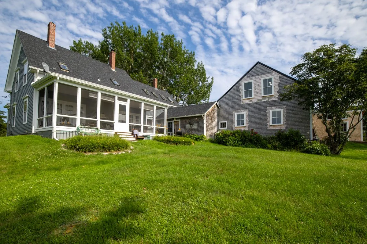 Rear exterior of cottage with screened porch and manicured lawn