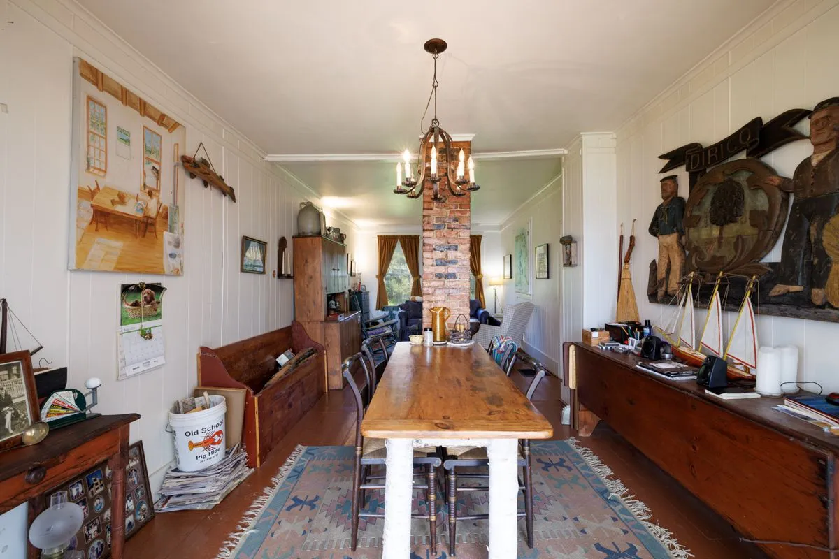 Long farmhouse dining room with chandelier and exposed brick fireplace
