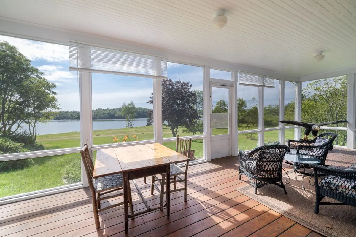 Bright sunroom with table and chairs overlooking the water