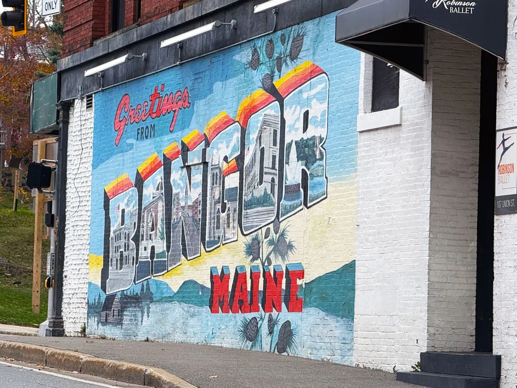 Greetings from Bangor Maine colorful postcard-style mural on brick building