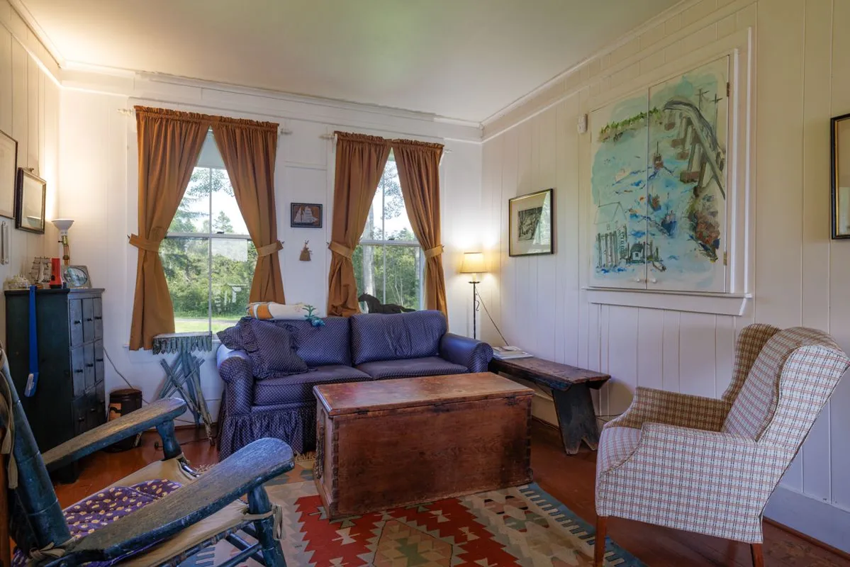 Cozy living room with blue sofa, wood chest, and coastal art