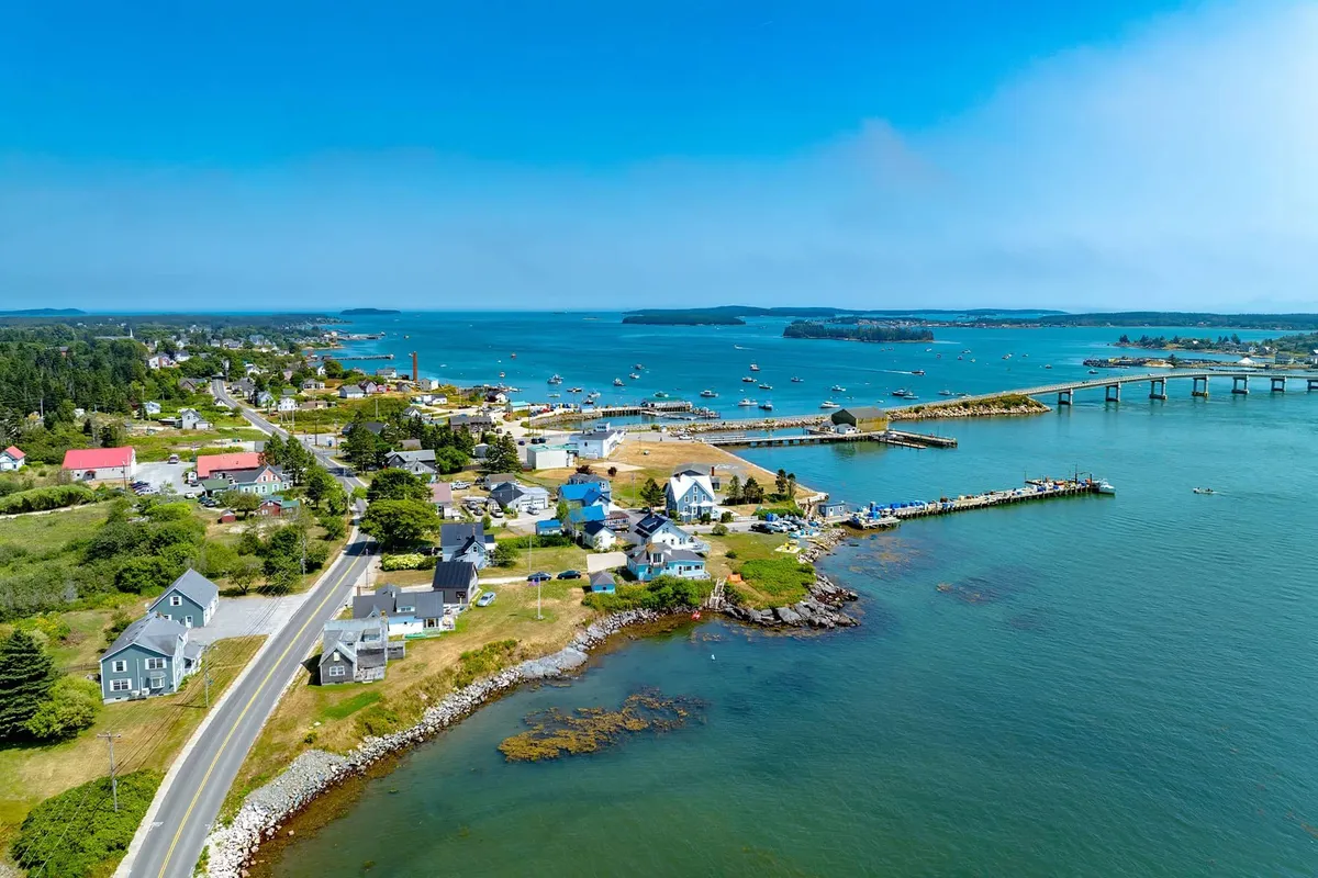 Wide aerial view of coastal Maine fishing village with piers and boats